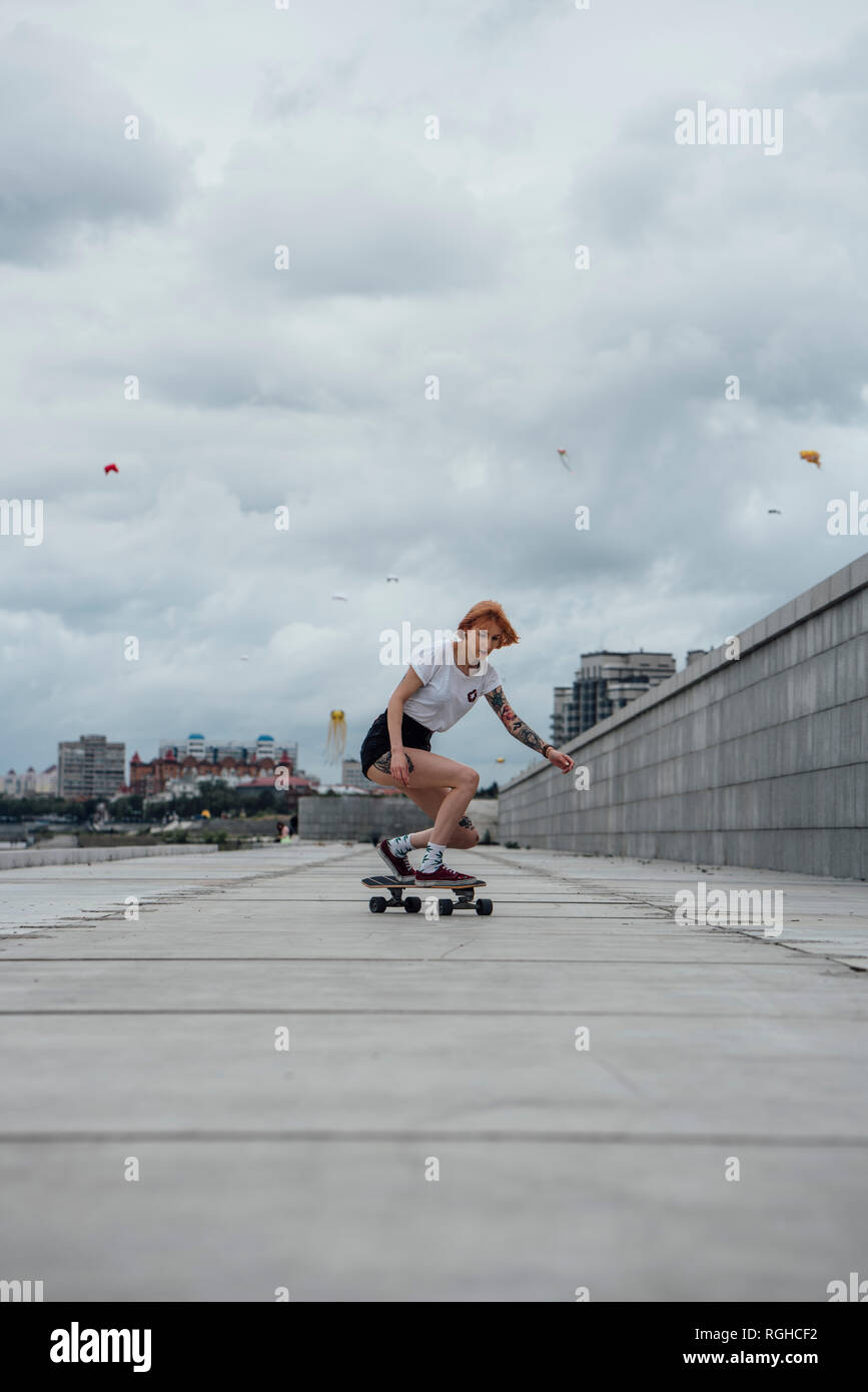 Giovane donna cavallo carver skateboard su un lungomare Foto Stock