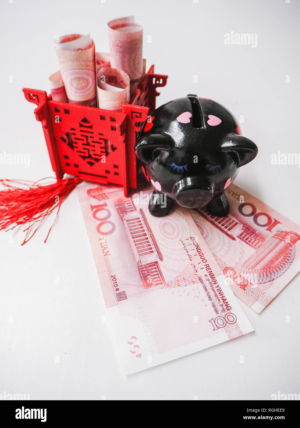 Nero salvadanaio e il Padiglione Cinese riempito di banconote, in piedi sul cinese 100 renminbi note contro uno sfondo bianco. Foto Stock
