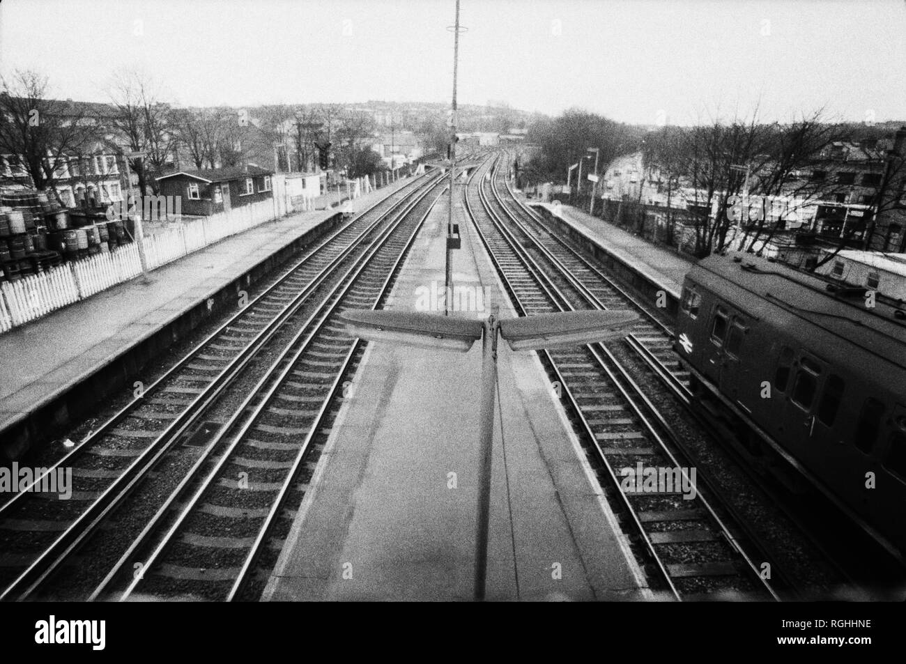 Archivio immagine monocromatica della piattaforma di una stazione ferroviaria di Londra sud con slam porta treno che passa attraverso, 1979, Londra, Inghilterra Foto Stock