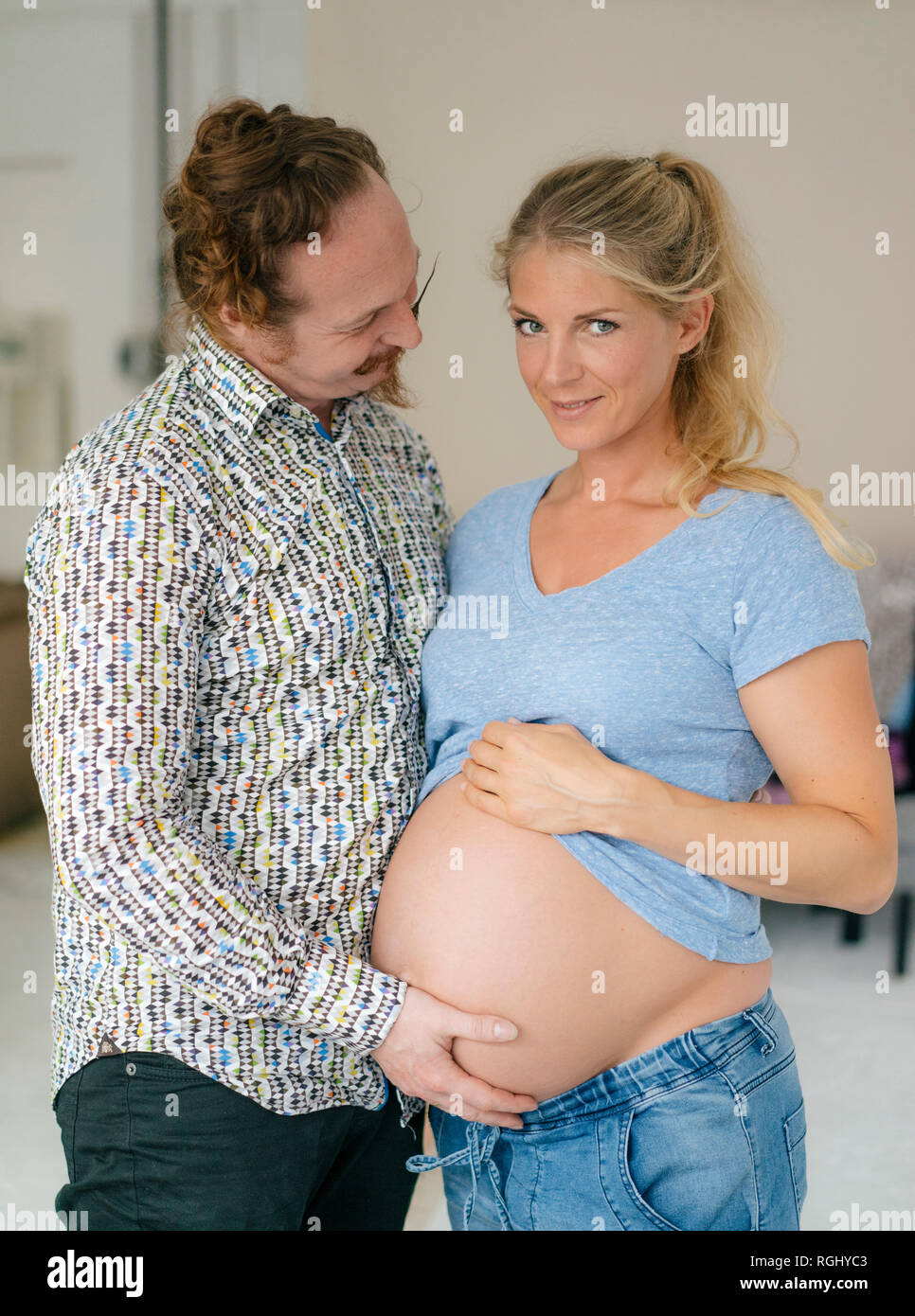 Uomo di toccare la pancia di sorridente donna in stato di gravidanza Foto Stock