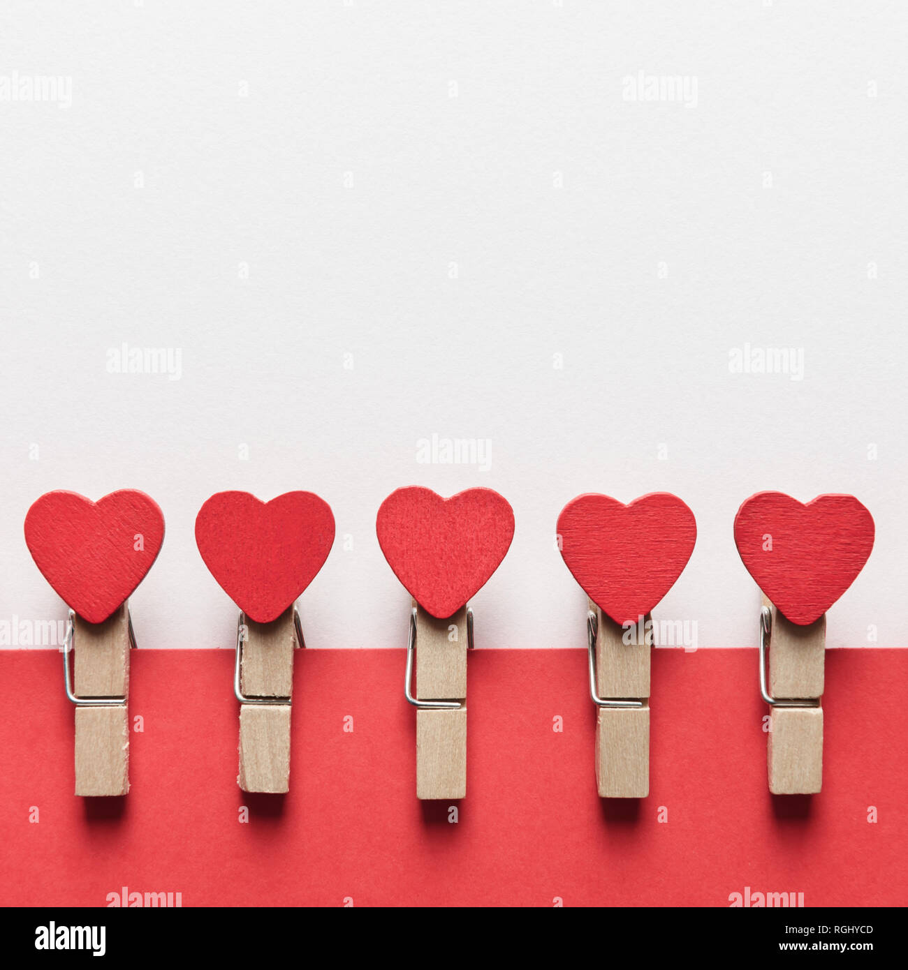 Vestiti di legno pin rosso con cuori di tessili. Il giorno di San Valentino sfondo, texture creative e il concetto di amore Foto Stock