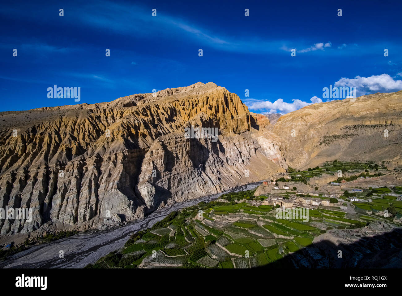 Panoramica vista aerea sulle case e il settore agricolo nei dintorni del villaggio con verdi campi di orzo, colorato ripide pareti rocciose in dista Foto Stock