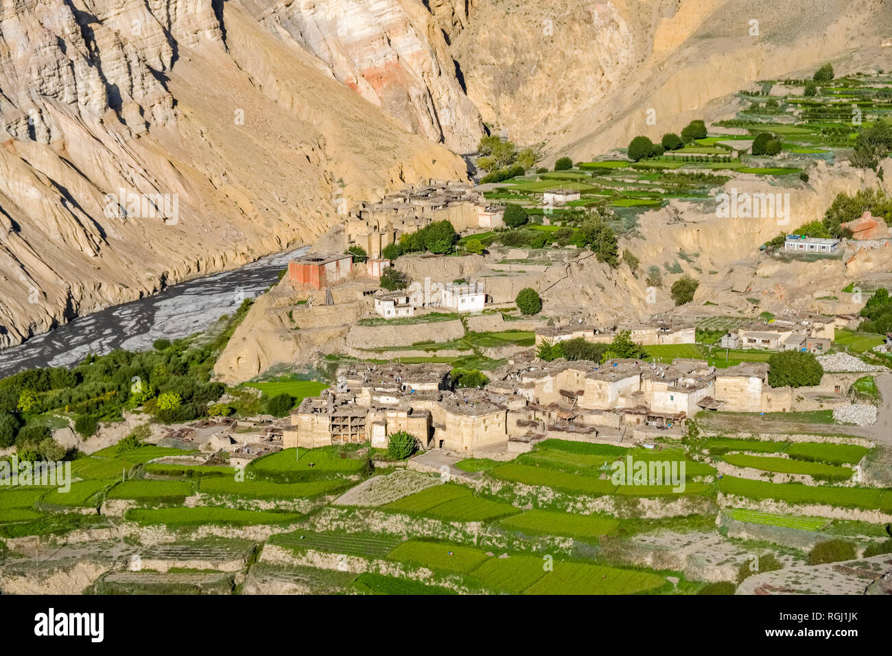 Panoramica vista aerea sulle case e il settore agricolo nei dintorni del villaggio con verdi campi di orzo, colorato ripide pareti rocciose in dista Foto Stock