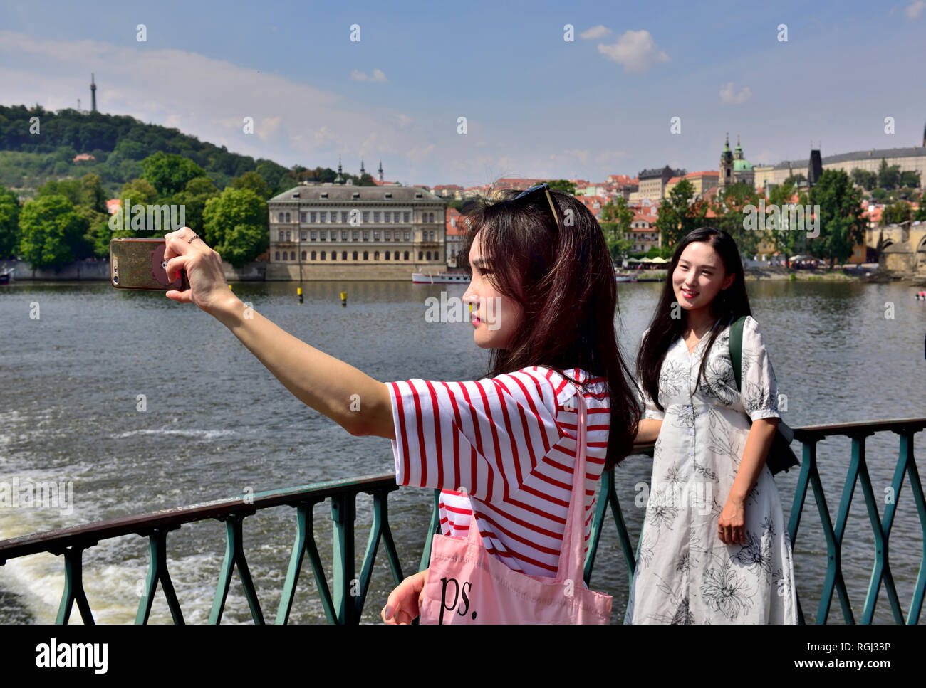 Donne giovani turisti affacciato sul fiume Vltava nella città vecchia Praga tenendo selfie, Repubblica Ceca Foto Stock
