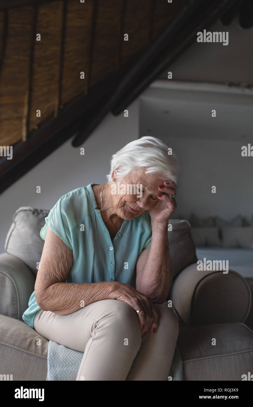 Preoccupato senior donna seduta nel salotto Foto Stock