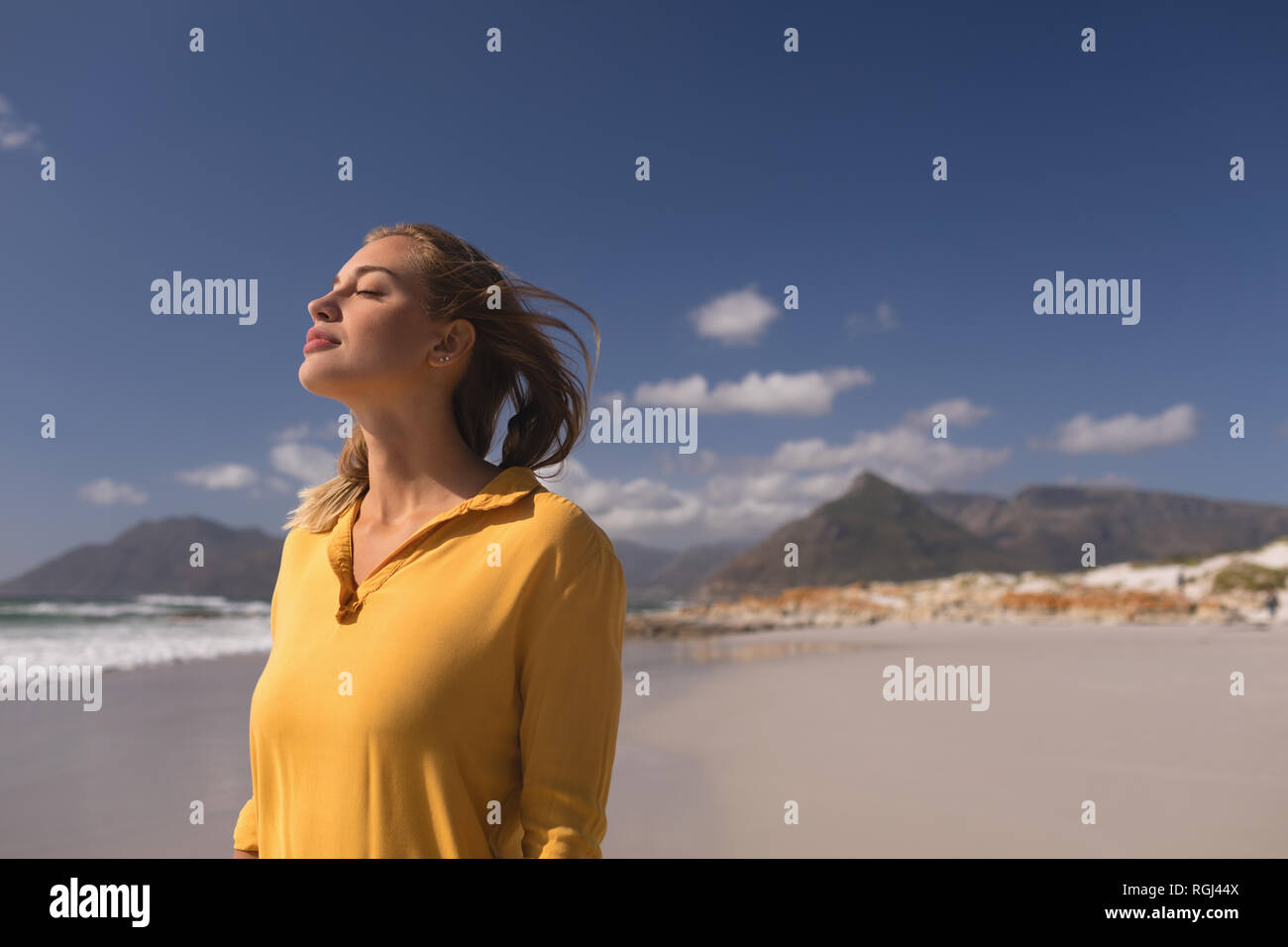 Donna in piedi con gli occhi chiusi sulla spiaggia Foto Stock