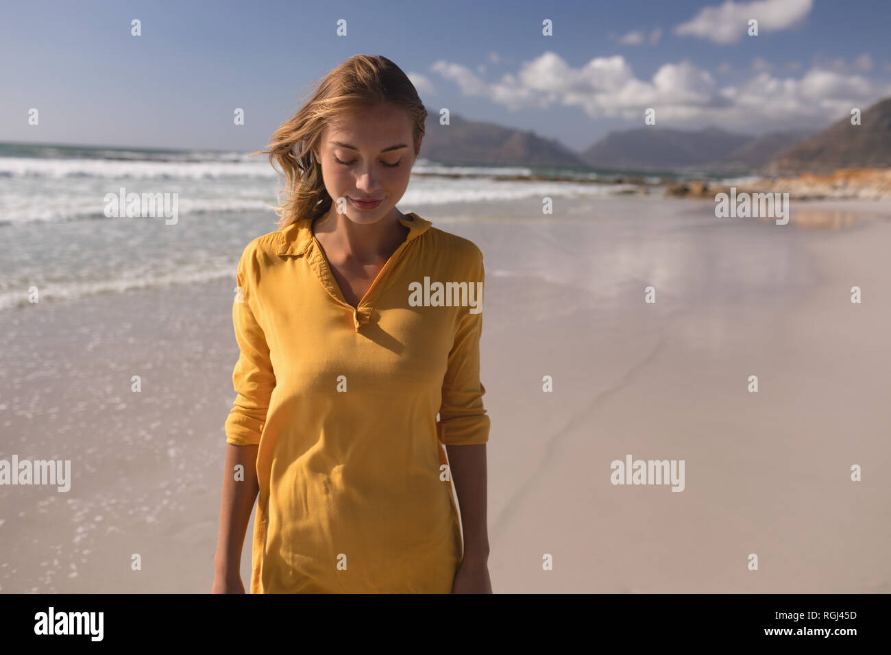 Donna in piedi con gli occhi chiusi sulla spiaggia Foto Stock
