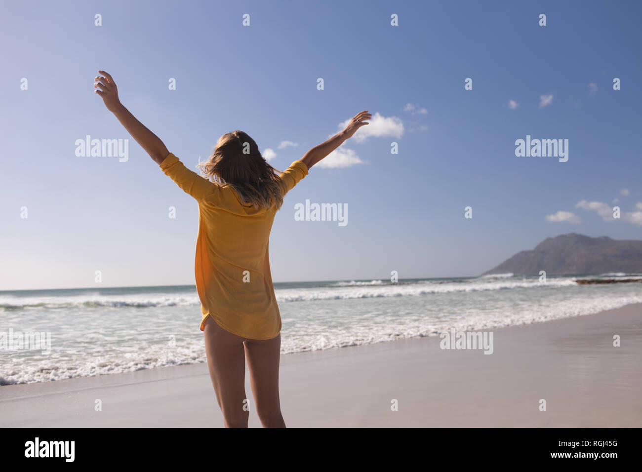 Donna in piedi con le braccia tese a beach Foto Stock