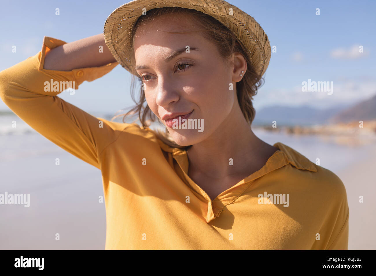 Donna in hat permanente sulla spiaggia Foto Stock