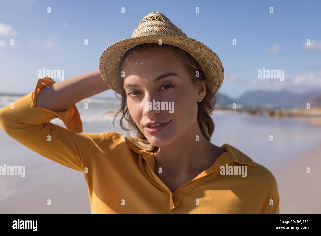 Donna in hat permanente sulla spiaggia Foto Stock
