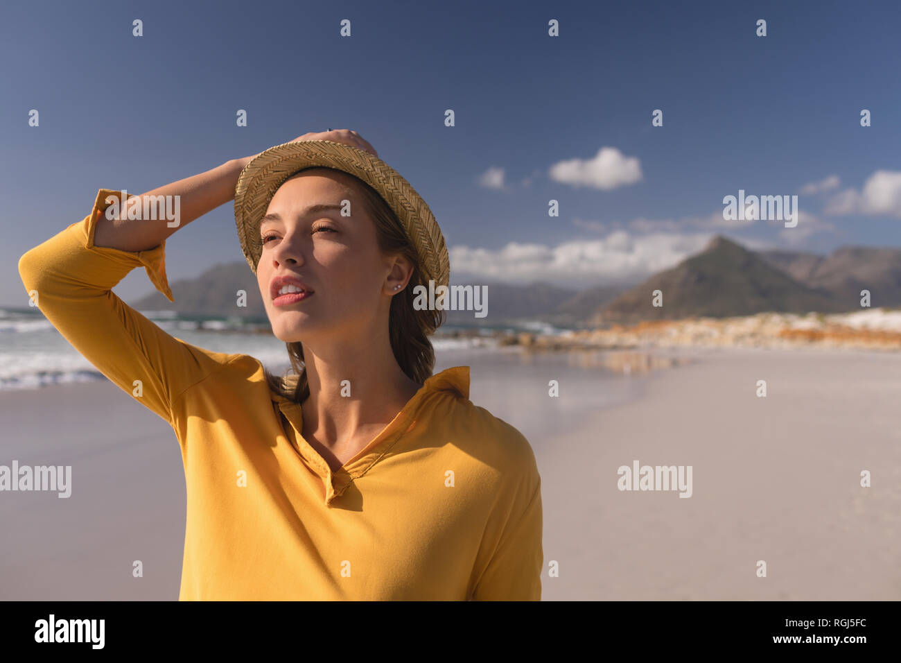 Donna in hat permanente sulla spiaggia Foto Stock