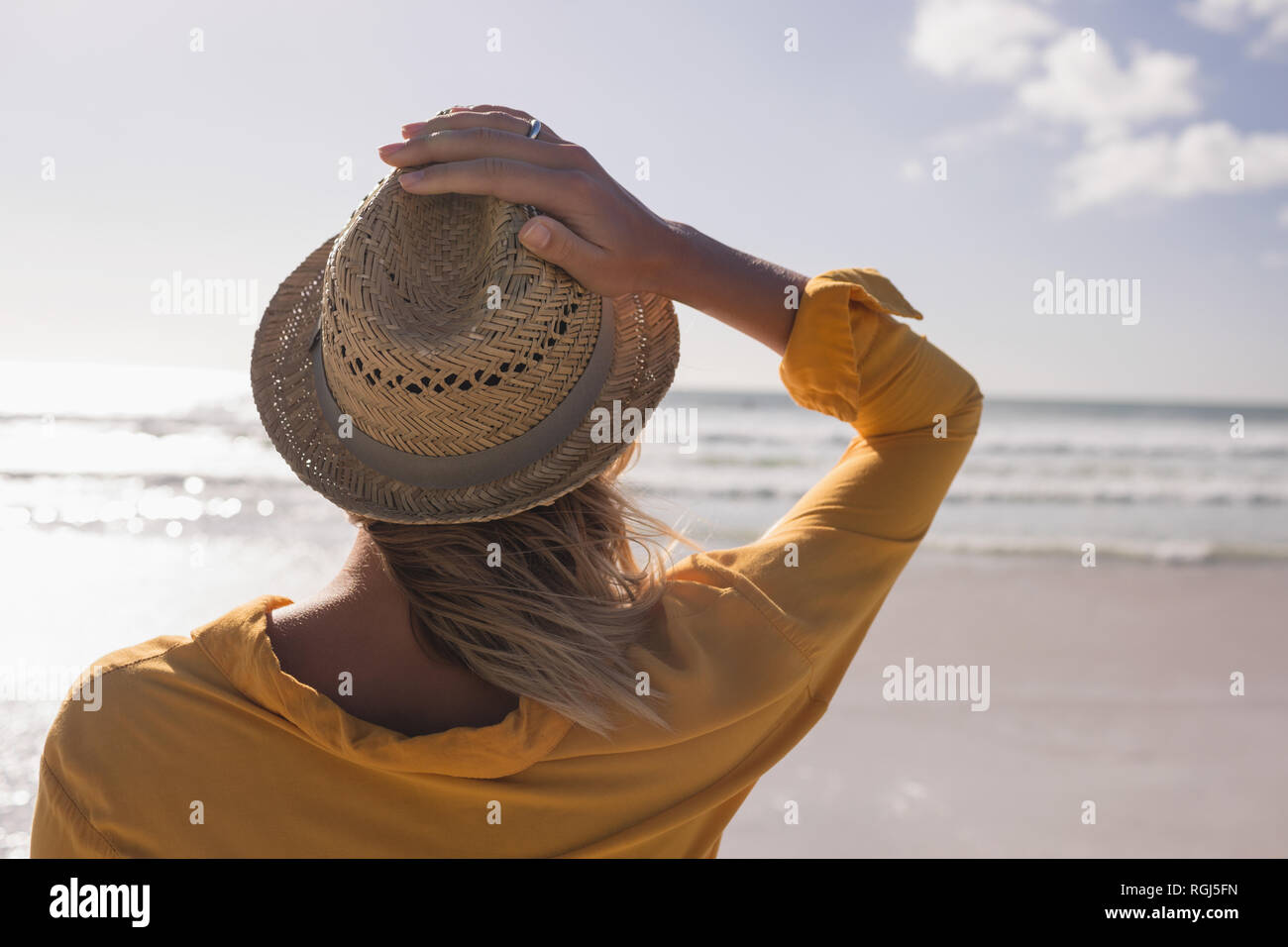Donna in hat permanente sulla spiaggia Foto Stock