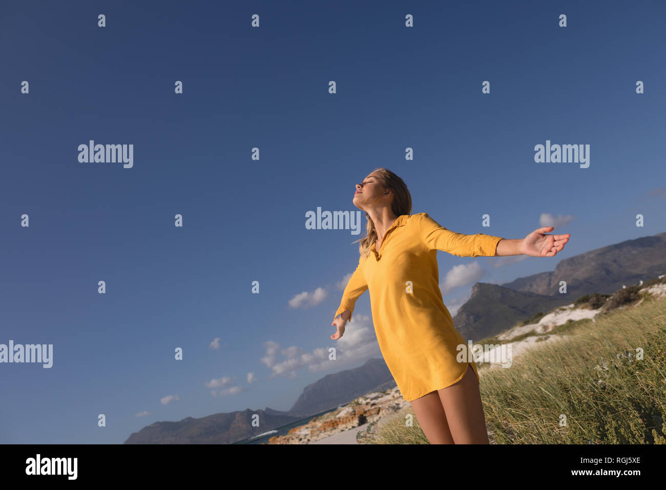 Donna in piedi con le braccia aperte sulla spiaggia Foto Stock