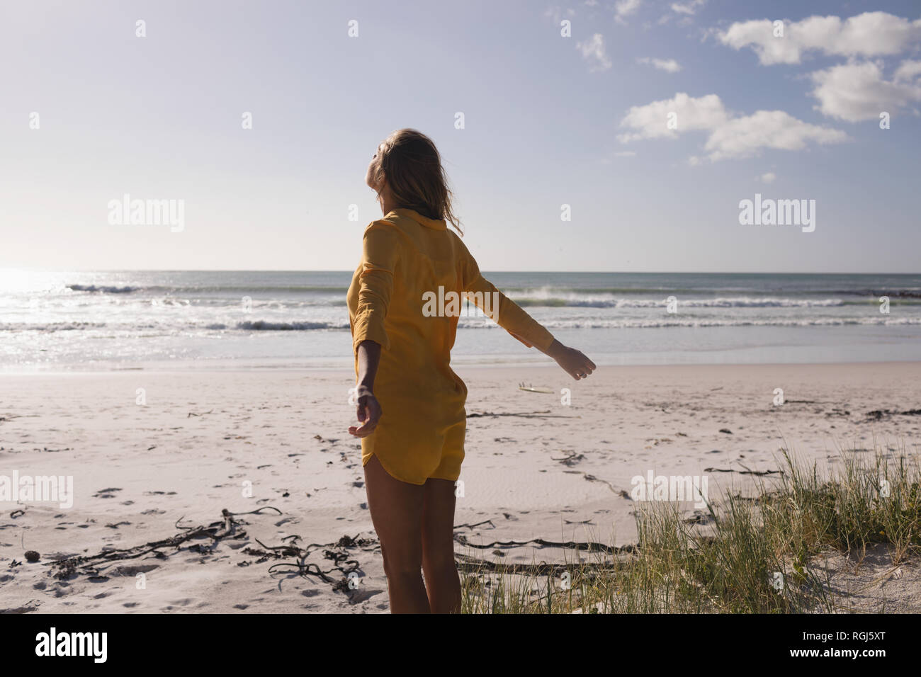 Giovane donna in piedi con le braccia aperte sulla spiaggia Foto Stock