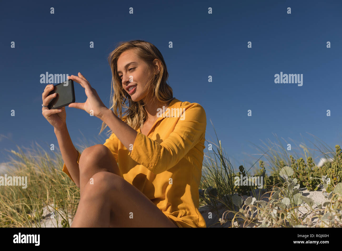 Donna prendendo selfie con telefono cellulare presso la spiaggia Foto Stock