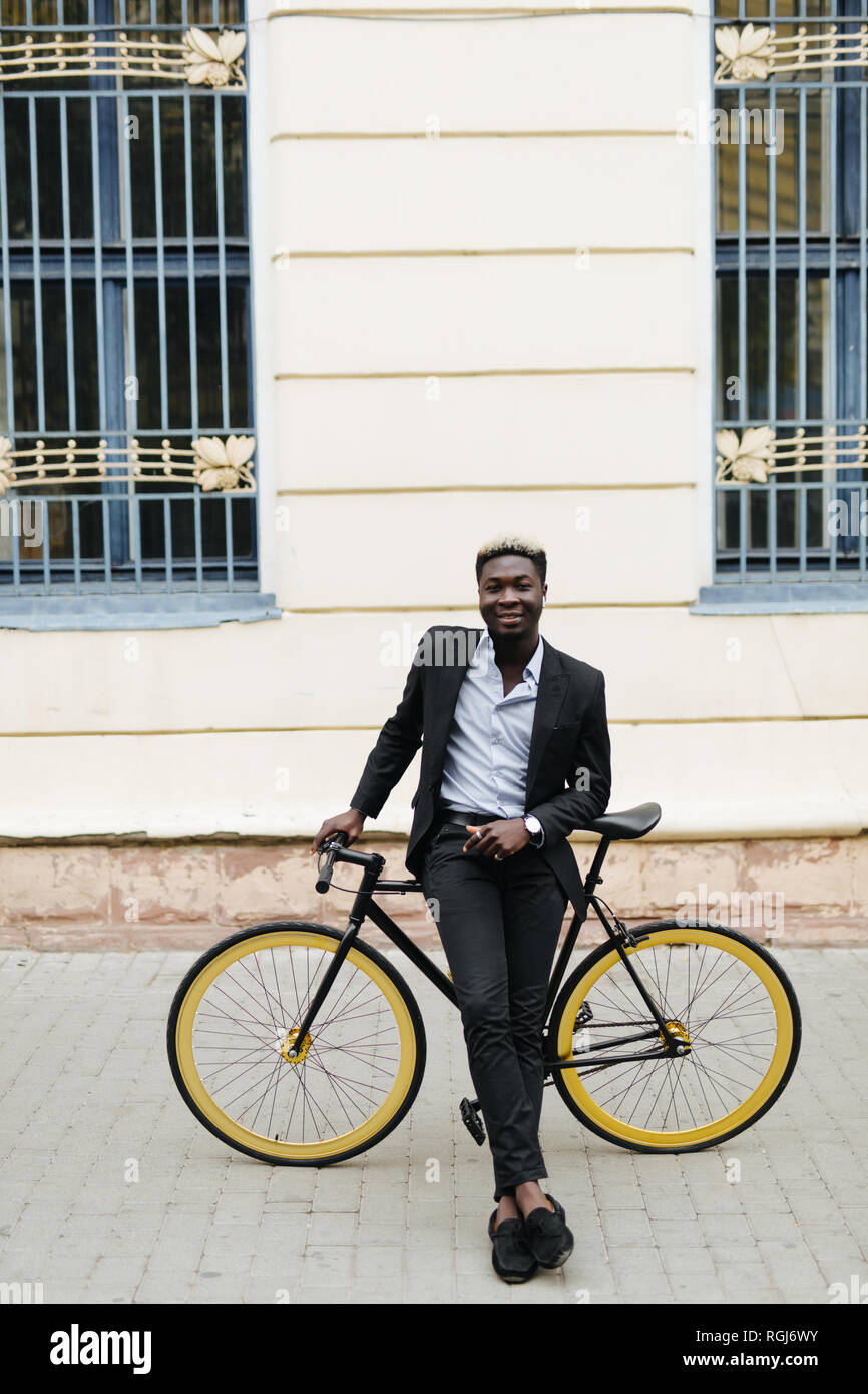 Bello l'uomo africano mi camminando per la strada con una bicicletta. L'uomo africano in casuals passeggiate all'aperto in città con una bici. Foto Stock