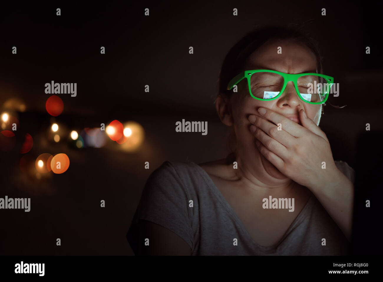 Stanco esaurito freelancer donna sta lavorando sul computer portatile e sbadigli a tarda notte nel suo ufficio a casa Foto Stock