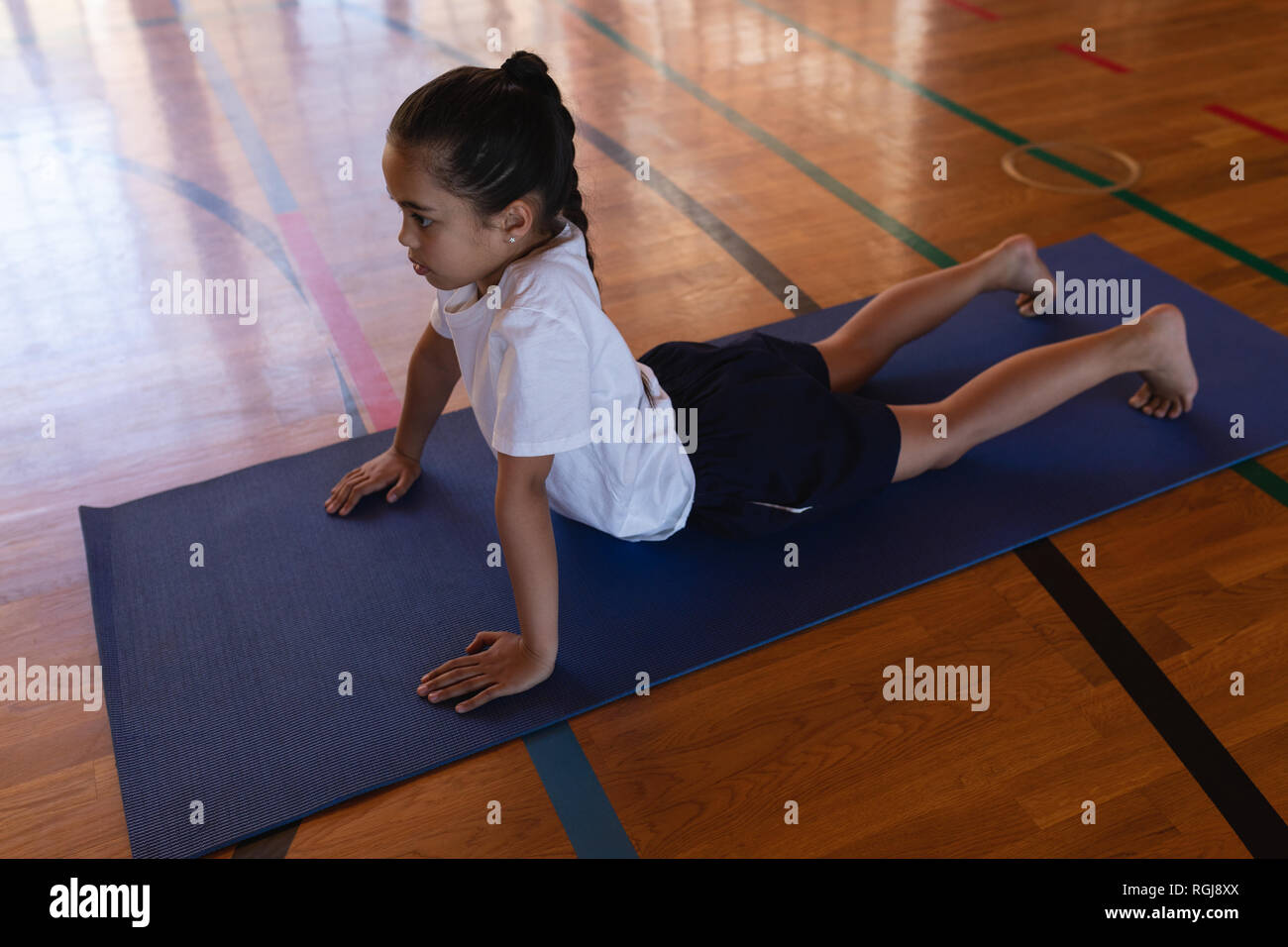 Schoolgirl fare yoga su un materassino yoga nella scuola Foto Stock