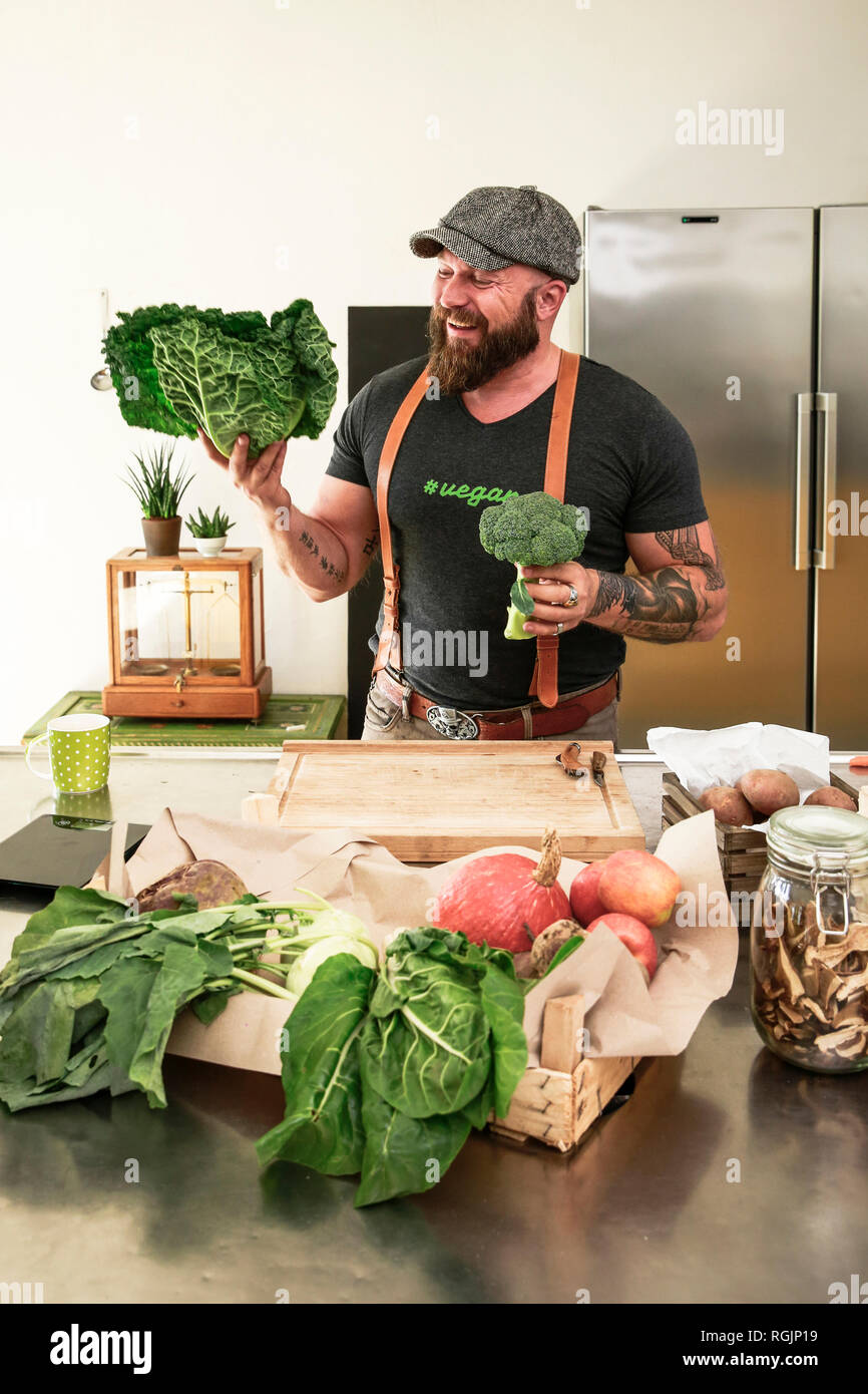 Uomo vegano scegliendo le verdure nella sua cucina Foto Stock