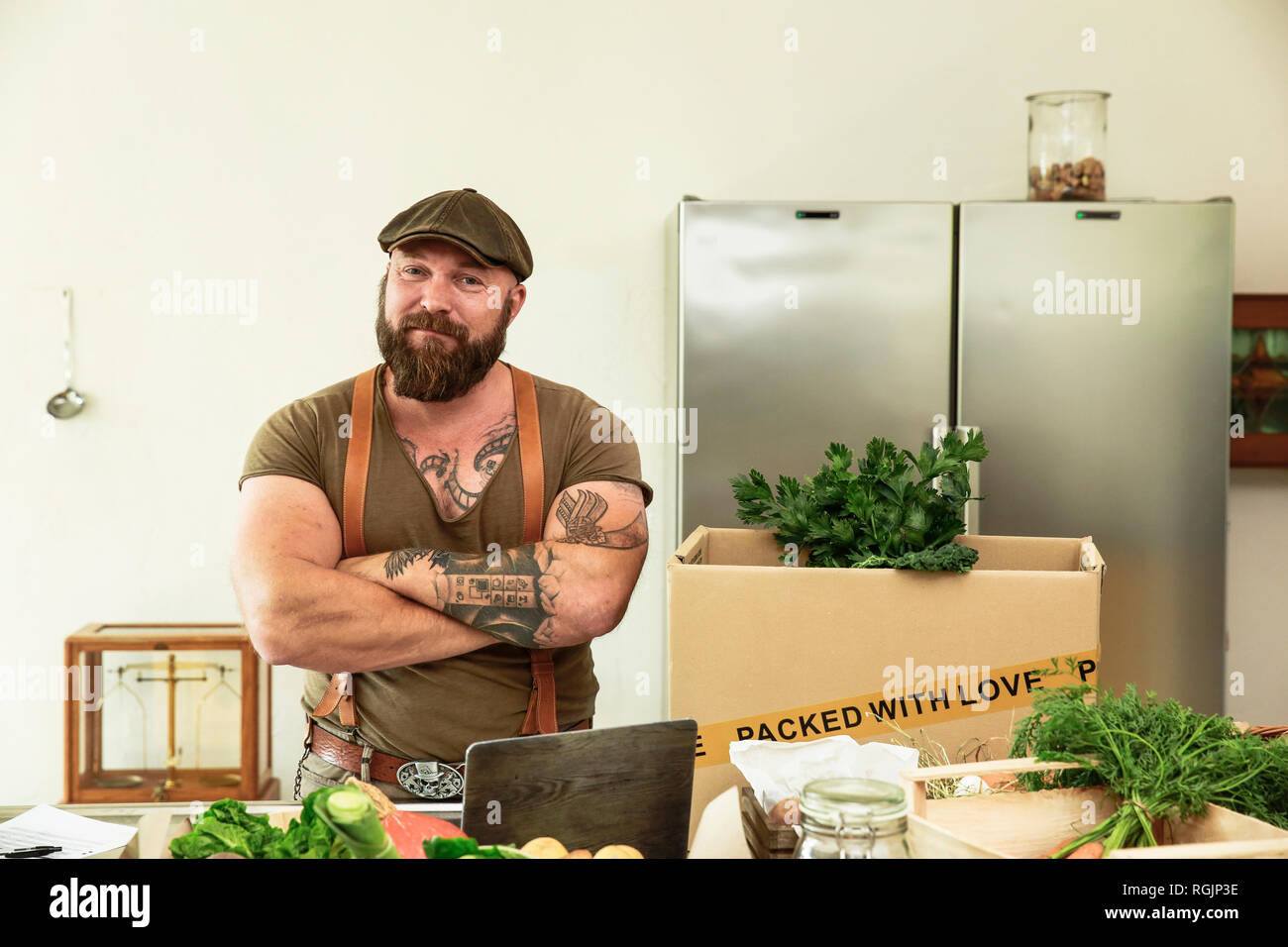 Il proprietario di un servizio di consegna per gli ortaggi biologici, in piedi fiero nella sua cucina Foto Stock