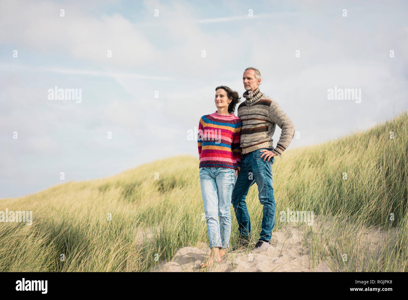 Coppia matura in piedi le dune, con bracci intorno Foto Stock