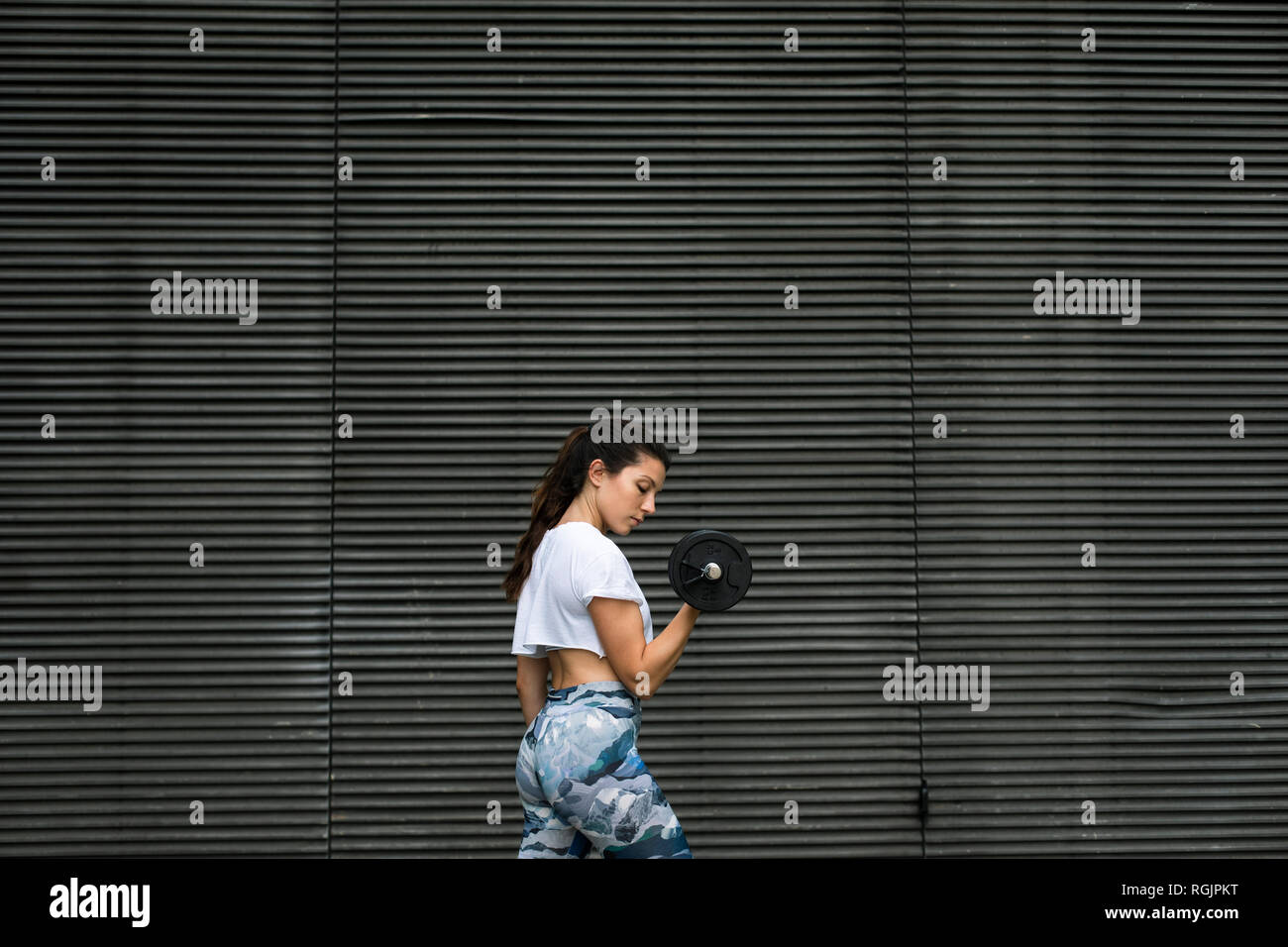 Giovane donna facendo allenamento peso all'aperto Foto Stock