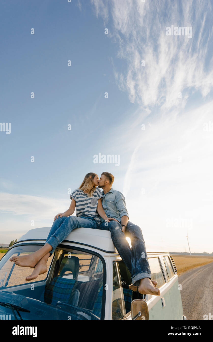 Giovane kissing sul tetto di un camper nel paesaggio rurale Foto Stock