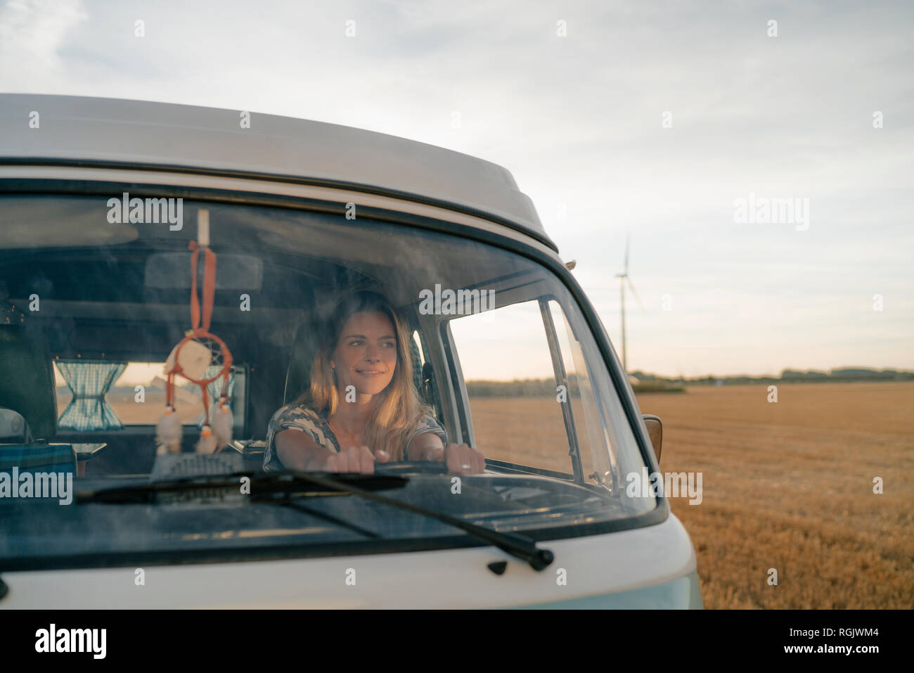 Sorridente giovane donna alla guida di camper van nel paesaggio rurale Foto Stock