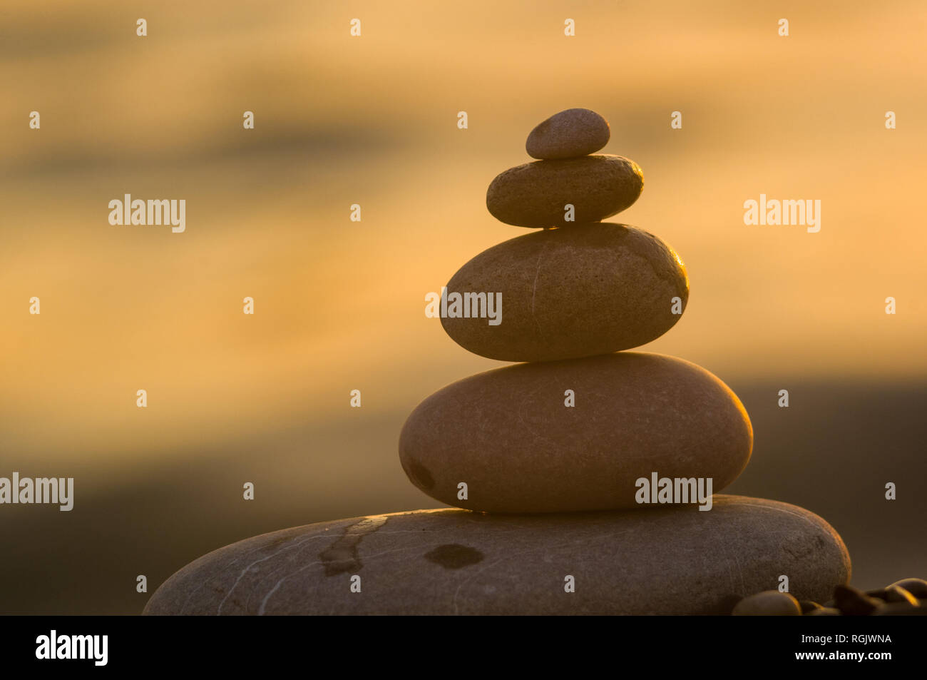 Piramide piegata Zen pietre ghiaia sul mare spiaggia al tramonto Foto Stock