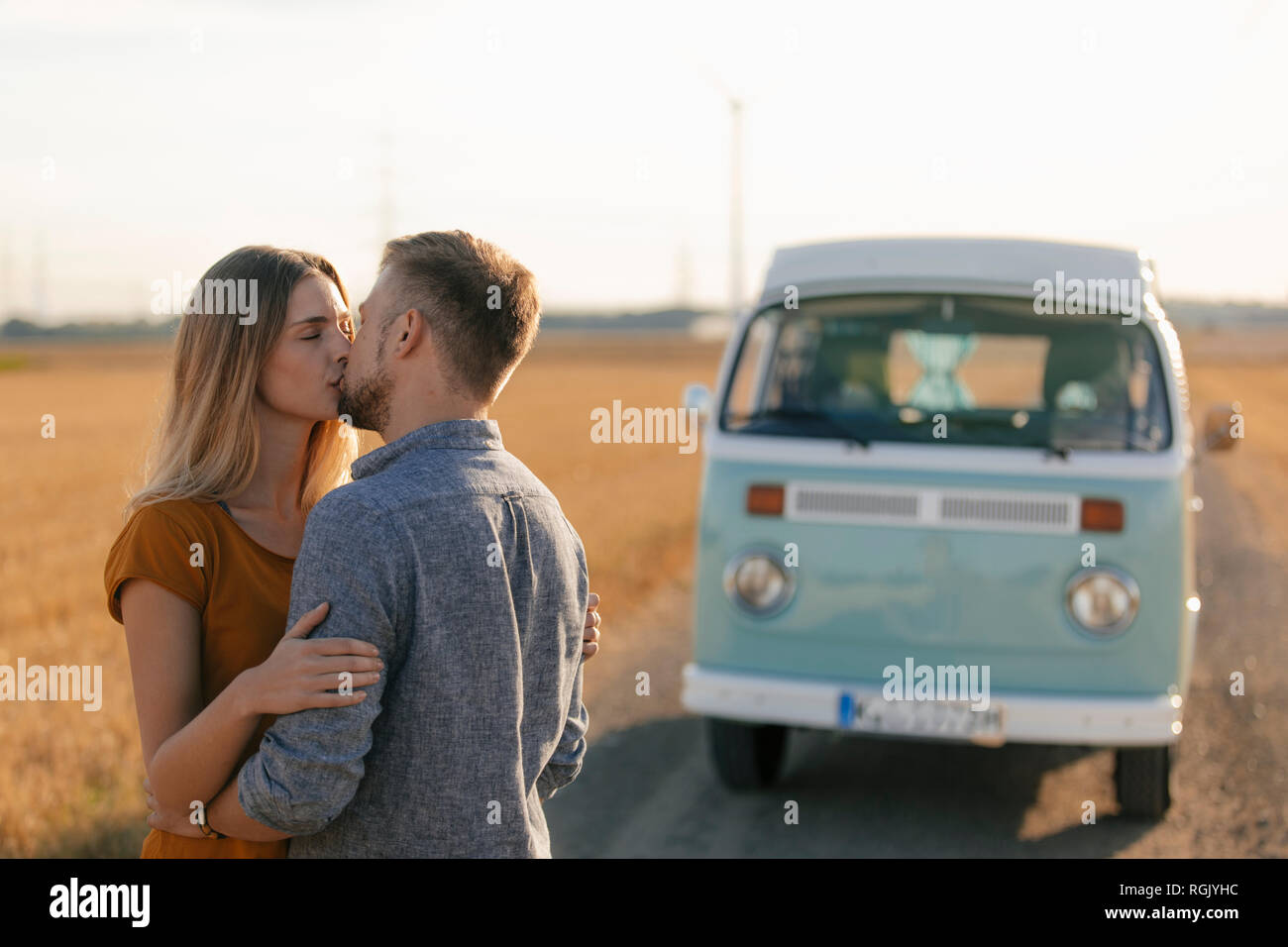 Coppia giovane kissing a camper van nel paesaggio rurale Foto Stock