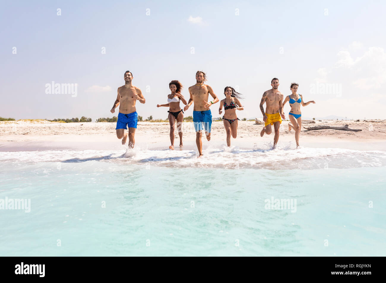 Gruppo di amici divertendosi sulla spiaggia, in esecuzione in acqua Foto Stock