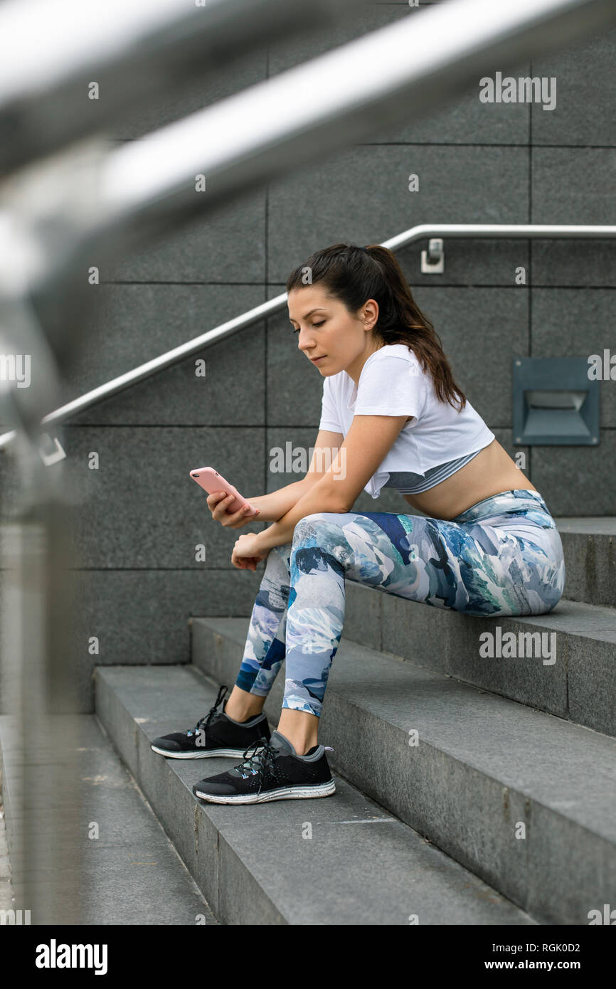 Montare la giovane donna seduta su scale tramite telefono cellulare Foto Stock