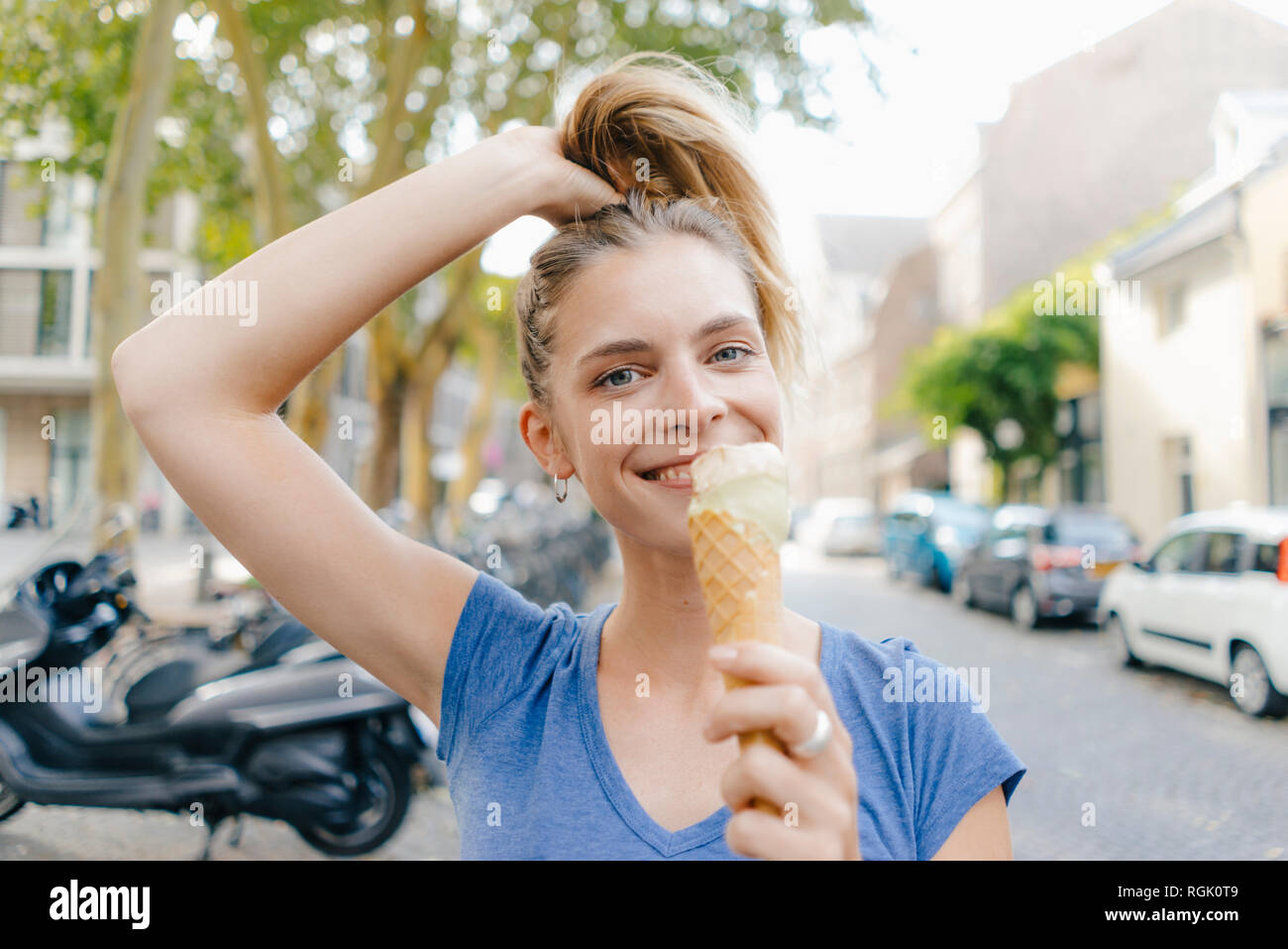 Paesi Bassi, Maastricht, ritratto di felice giovane donna bionda tenendo cono gelato in città Foto Stock