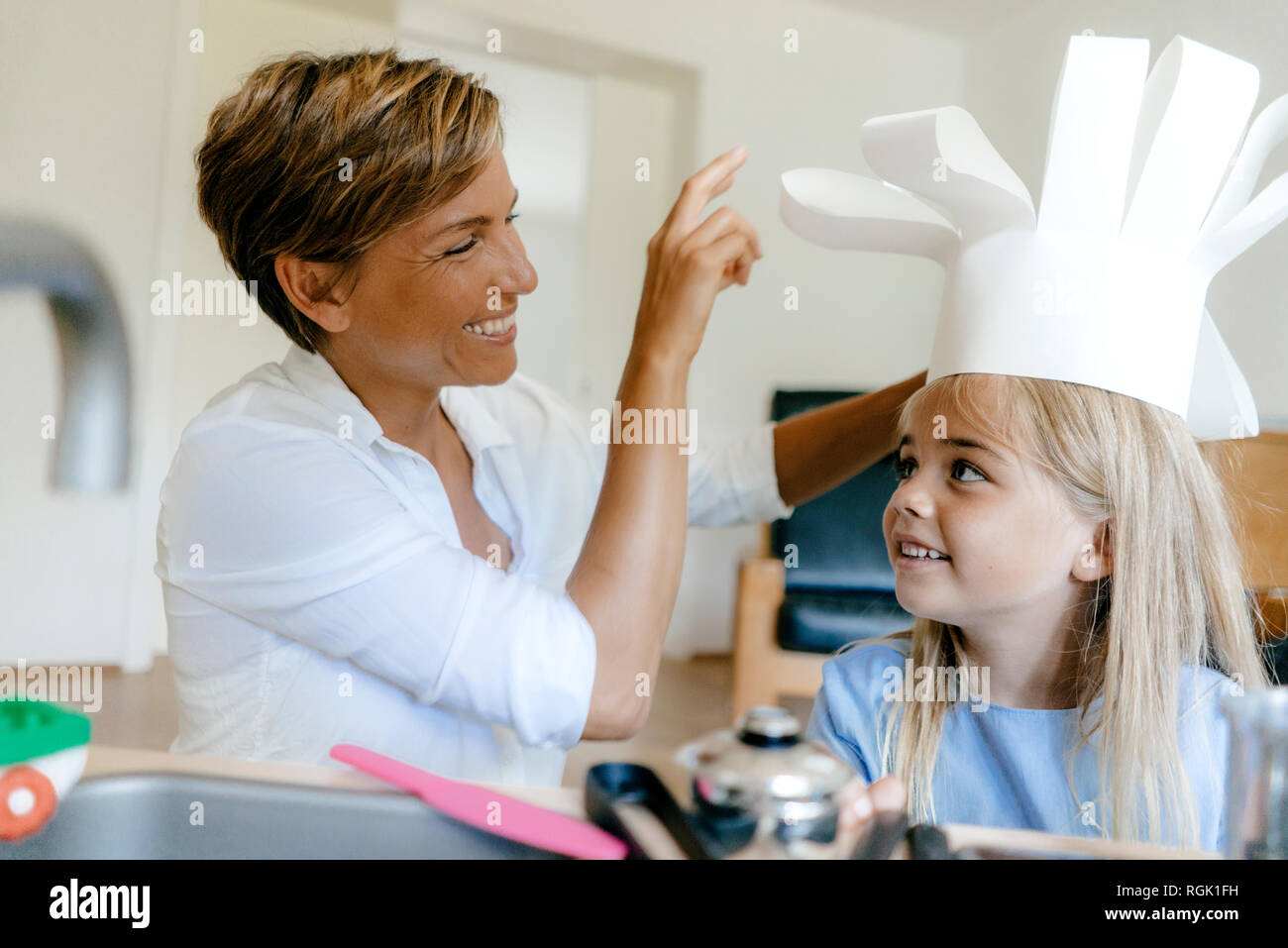 Felice madre e figlia giocando a casa e mettere su chef hat Foto Stock