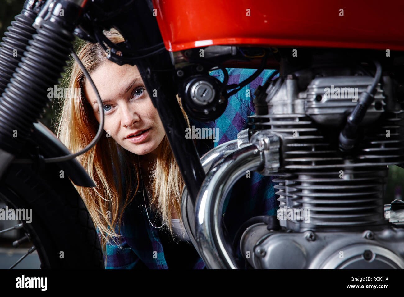 Ritratto di fiducioso giovane donna dietro il motociclo Foto Stock