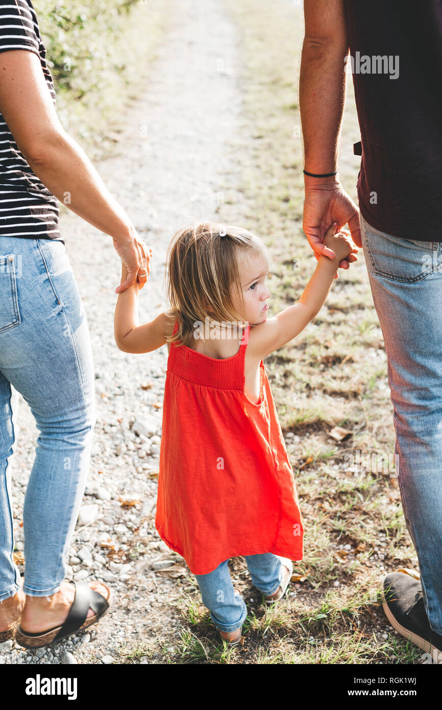 Ragazza camminare su parent le mani su un percorso di campo Foto Stock