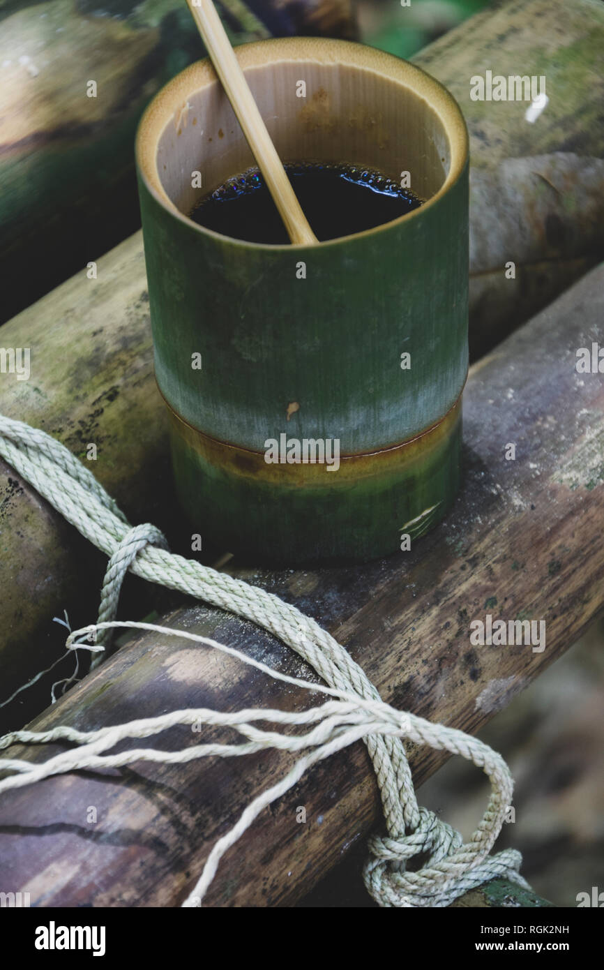 Bio freschi fatti di bambù e coppa cucchiaio riempiti a caldo con delizioso caffè caldo su un banco nella giungla in Thailandia. Ecoturismo Foto Stock