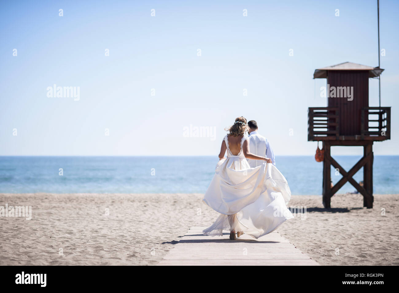 Vista posteriore della coppia di sposi godendo di giorno di nozze di camminare sulla spiaggia Foto Stock