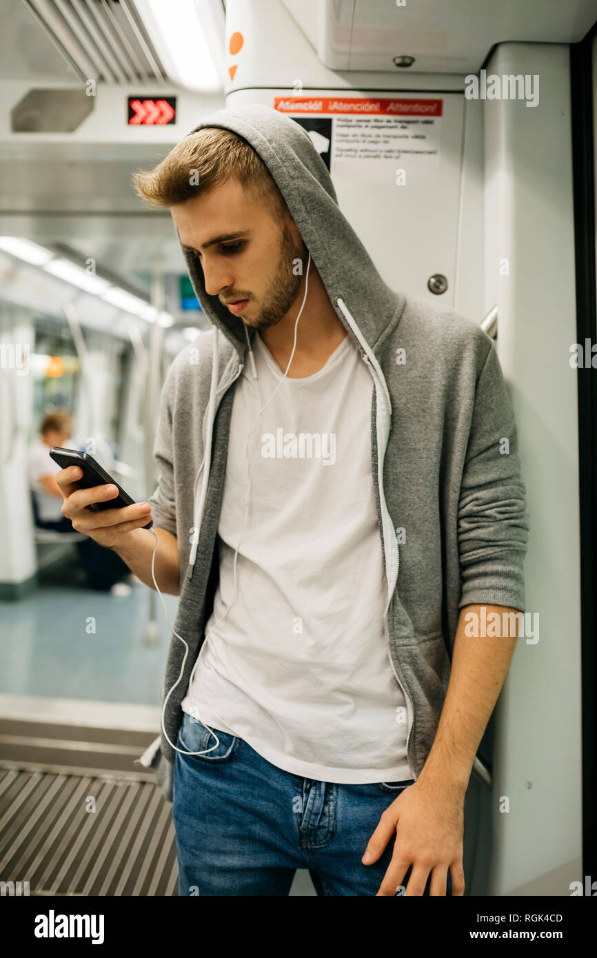 Giovane uomo utilizza lo smartphone in metro Foto Stock