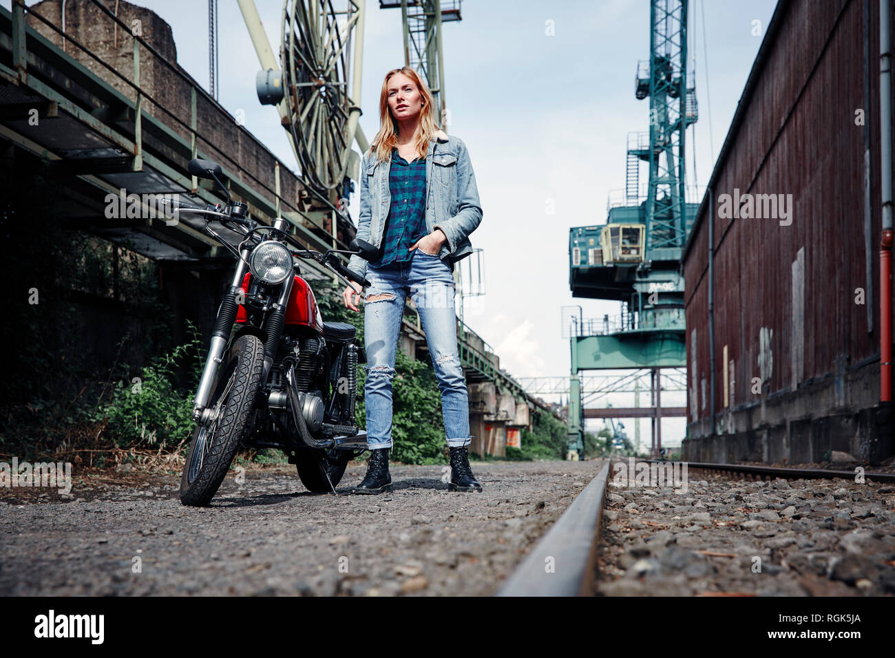 Ritratto di fiducioso giovane donna in piedi accanto al motociclo Foto Stock