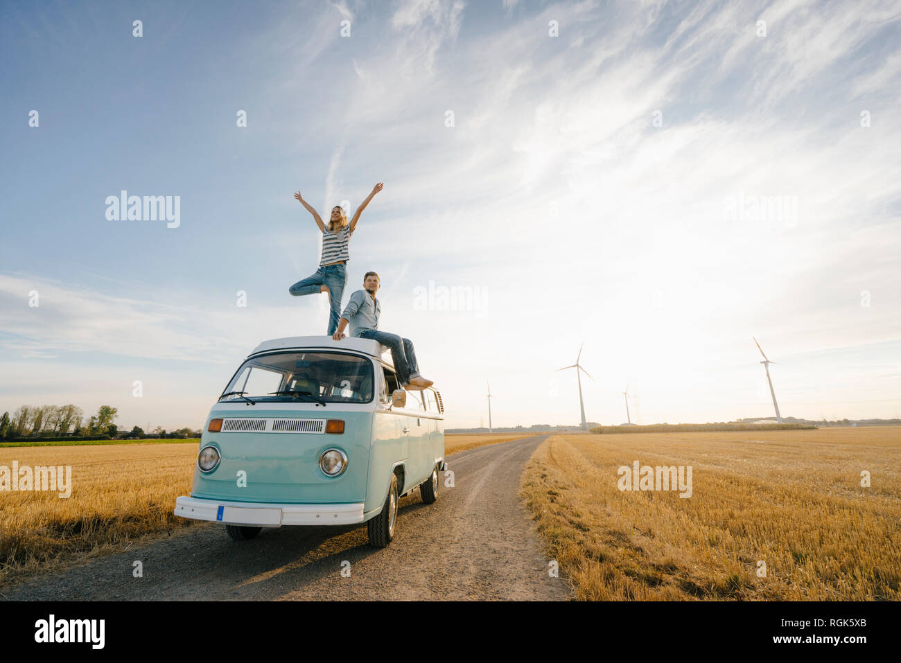 Coppia giovane sul tetto di un camper nel paesaggio rurale Foto Stock