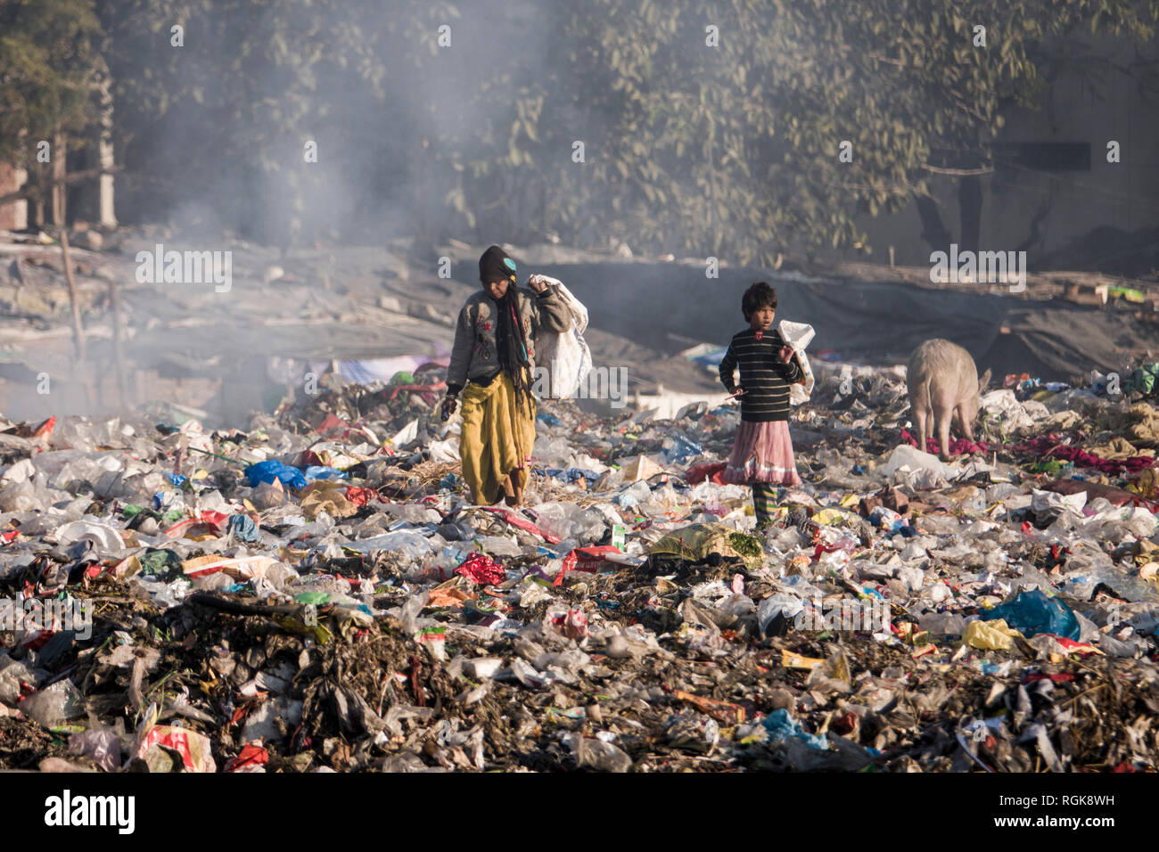 Famiglia di ragpickers rovistare attraverso il cestino a discarica a Rishikesh, Uttarakhand, India Foto Stock