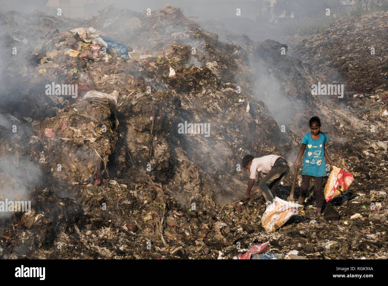 I bambini la raccolta di materiali di riciclo tra fumo tossico a discarica a Rishikesh, Uttarakhand, India Foto Stock