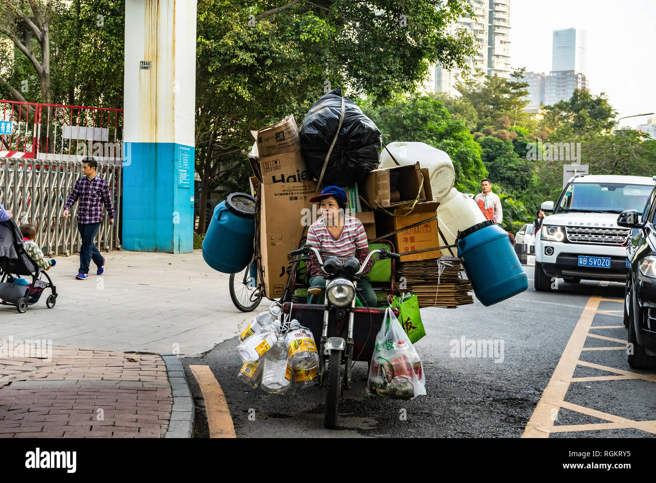 In Cina il riciclaggio di plastica, un cestino picker raccoglie le bottiglie di plastica e scatole di cartone da riciclare a Shenzhen, Cina Foto Stock