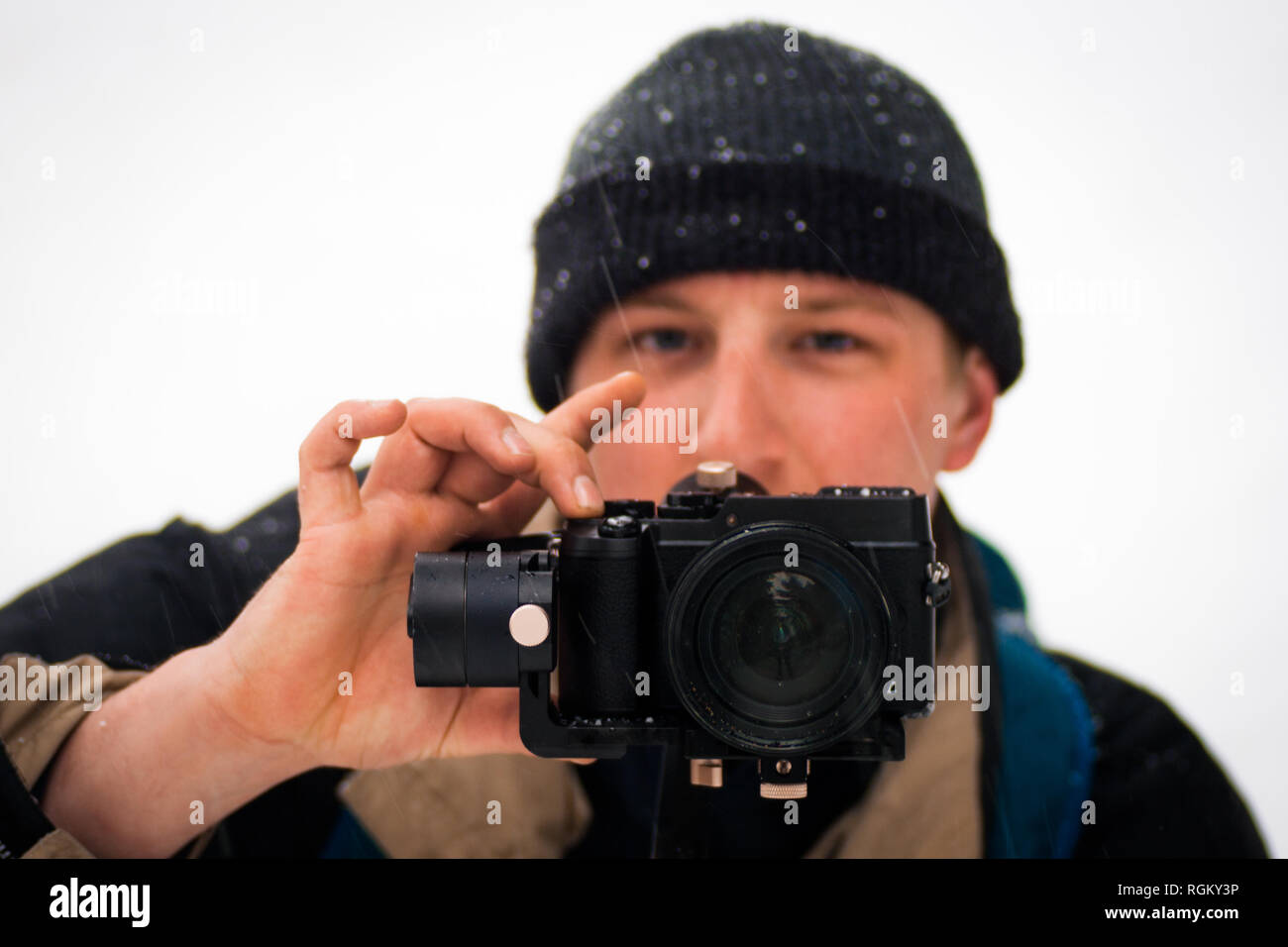 La messa a fuoco della fotocamera di un giovane caucasico modello da uomo, fotografia amatoriale, riprese al di fuori nella neve fredda/tempo piovoso. Di fronte alla macchina fotografica, concentrati Foto Stock