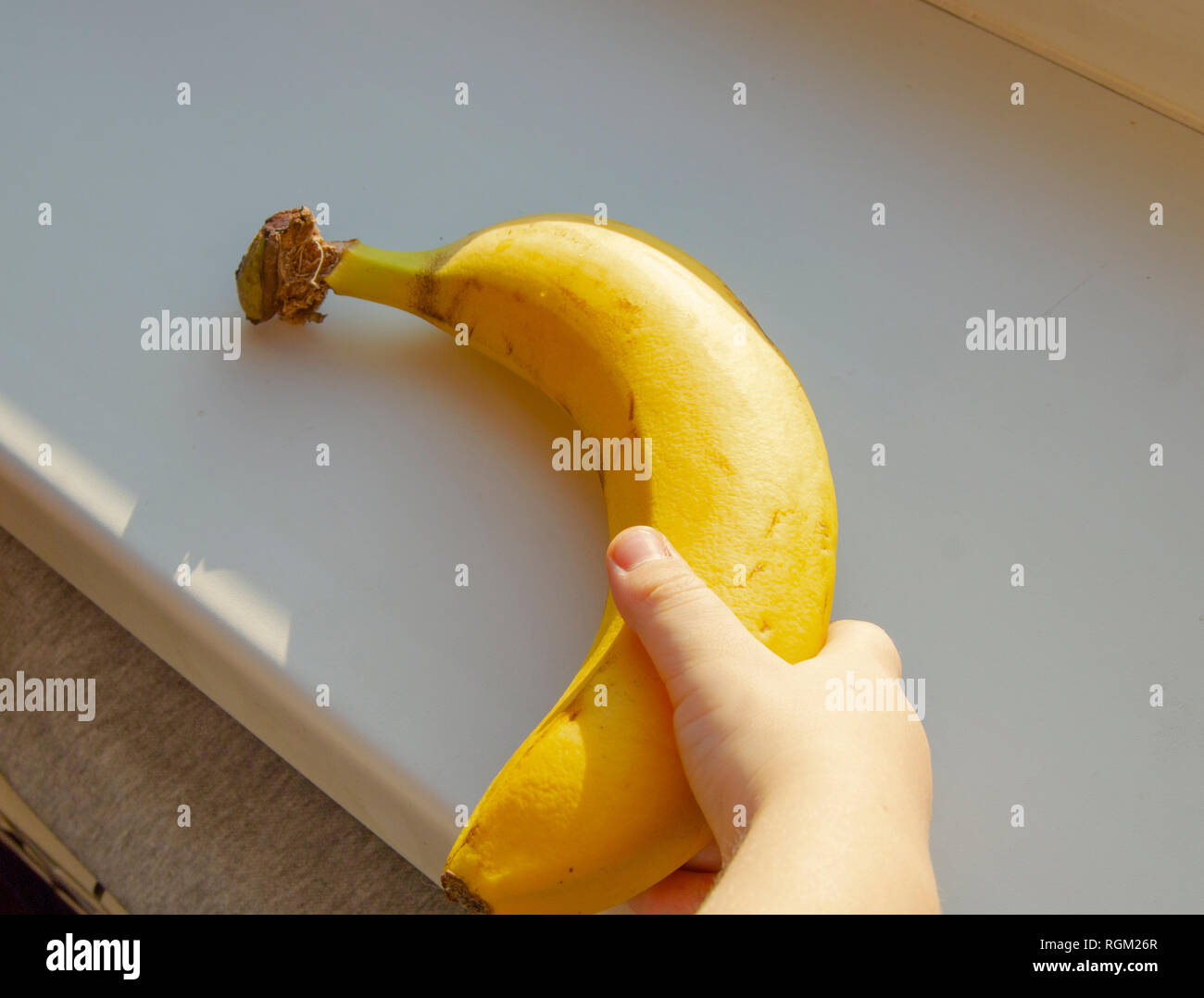 Baby mano azienda banana, close-up la luce del sole. Foto Stock