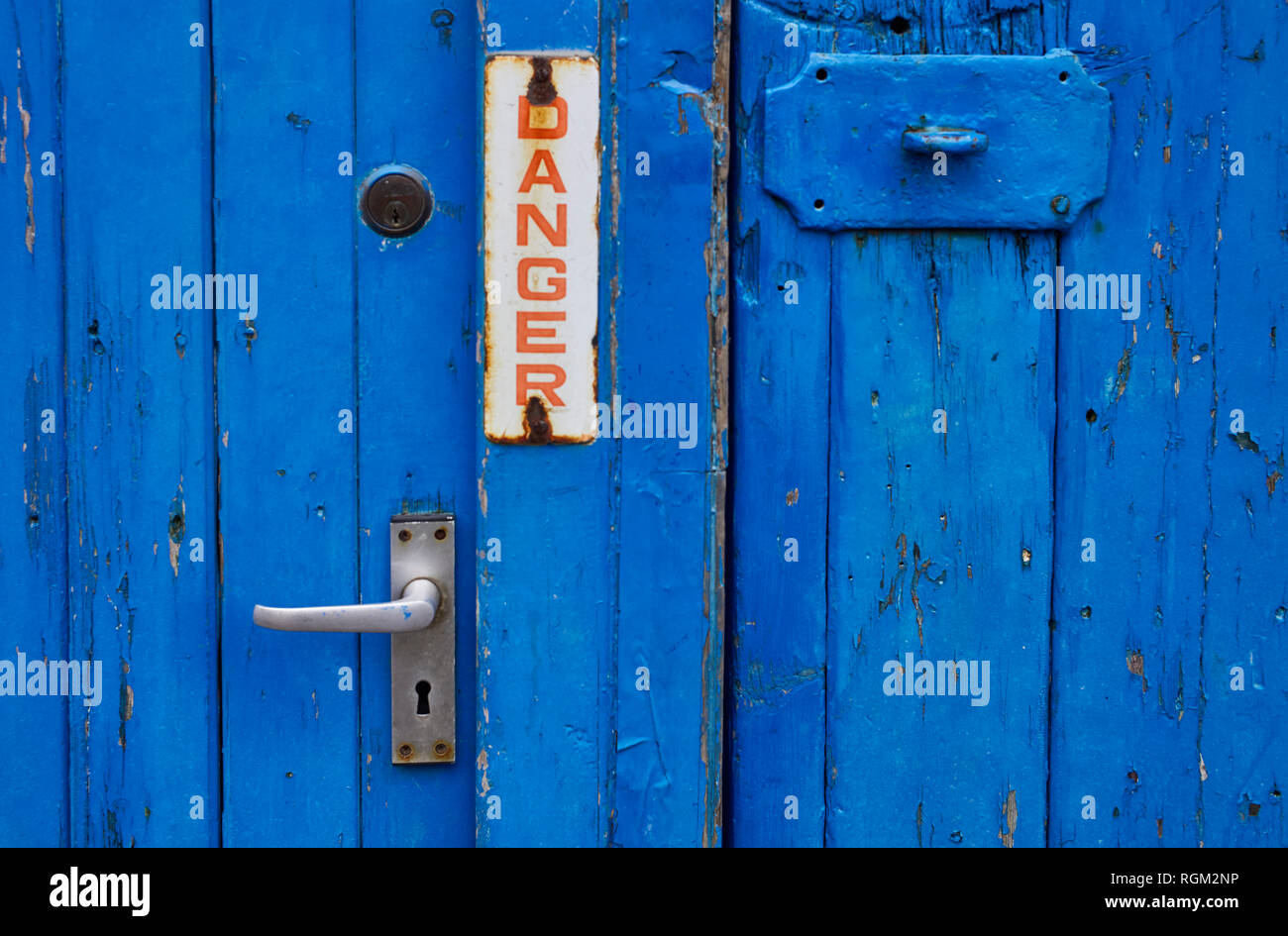 Dipinto di blu porta con smaltato segno di pericolo Foto Stock