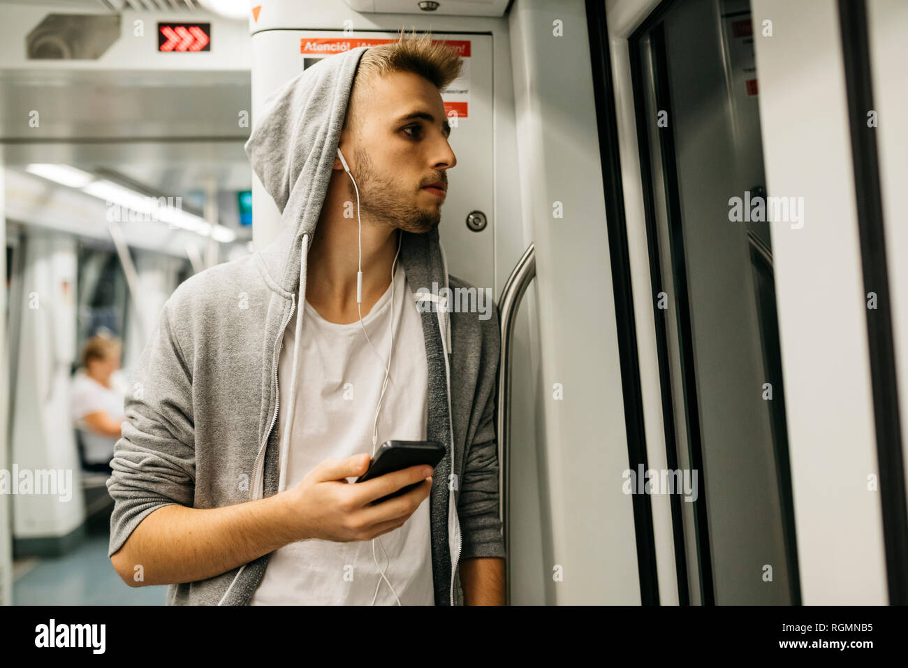 Giovane uomo utilizza lo smartphone in metro Foto Stock