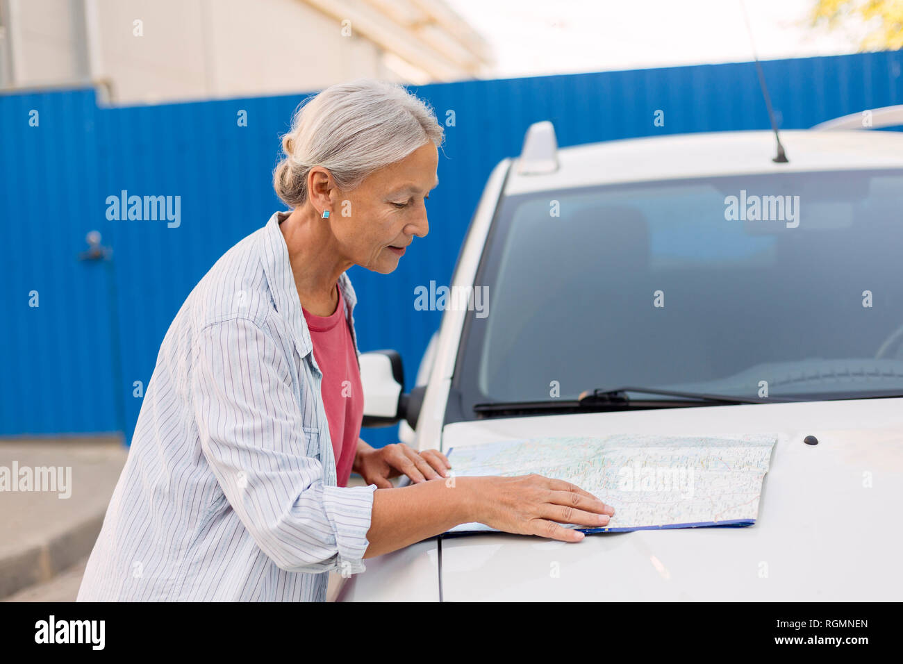 Senior donna che guarda la mappa stradale sulla sua automobile cofano Foto Stock