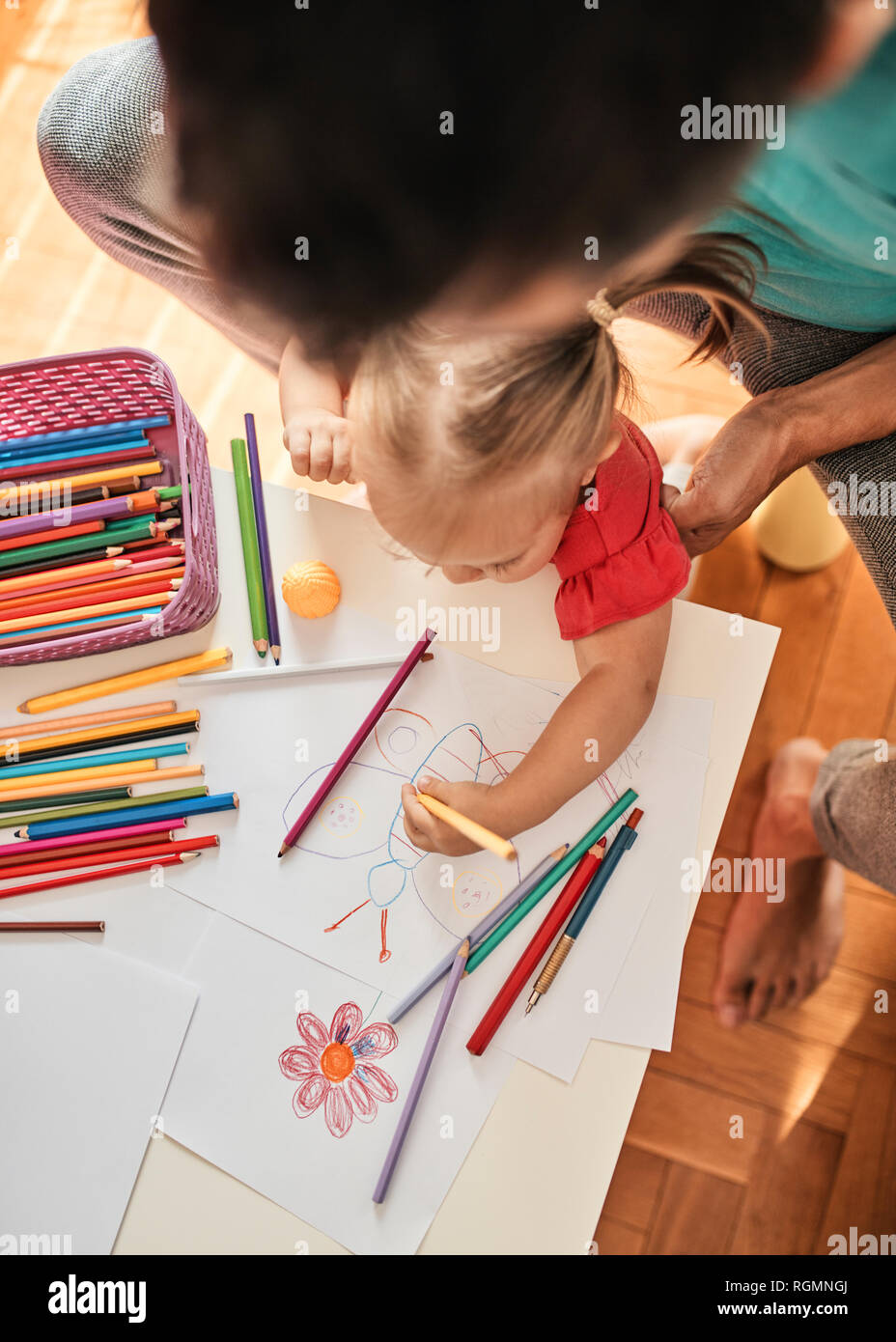 Bambina il disegno con la matita colorata mentre suo padre osservando il suo, vista dall'alto Foto Stock